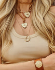 Model wearing various gold Texas pendants and love leather cuff