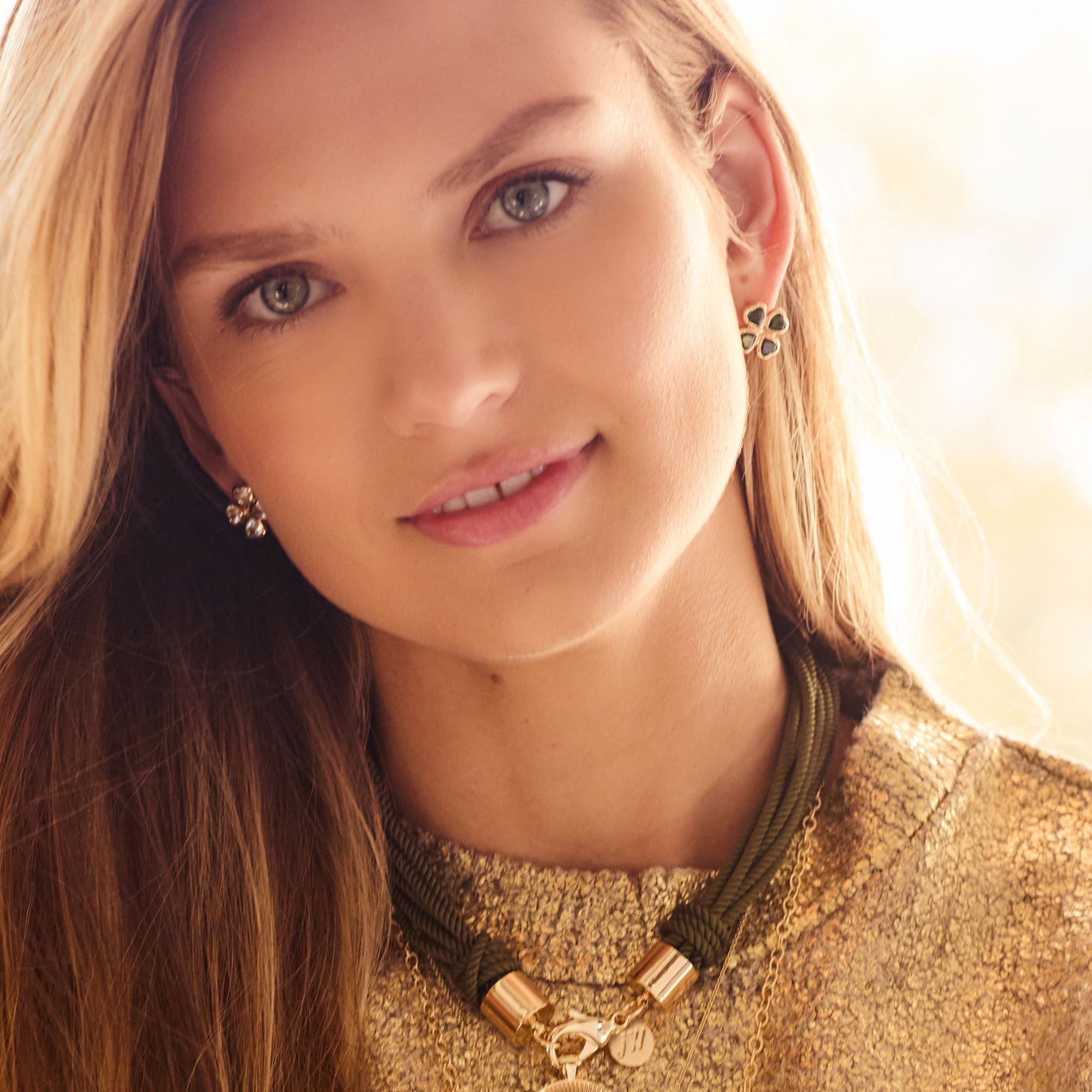 Model wearing gold four leaf clover earrings