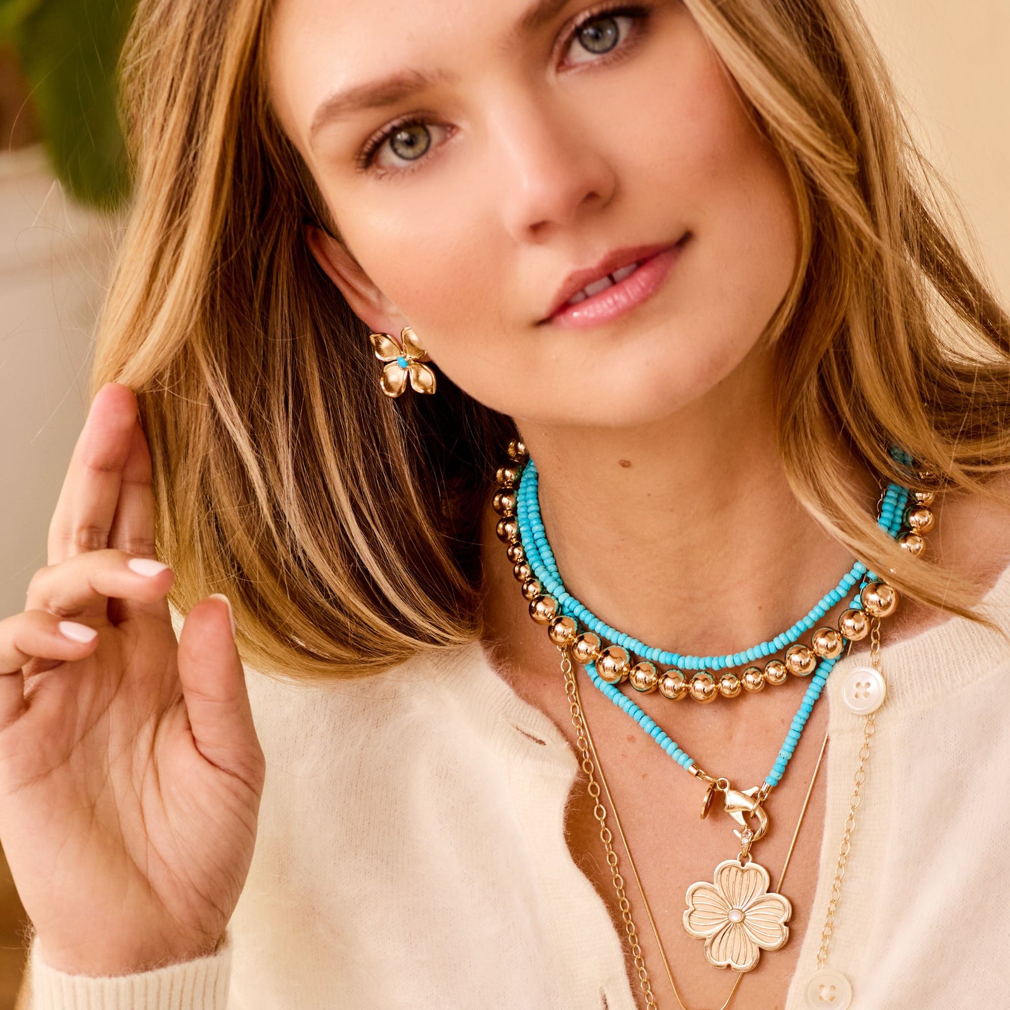 Model wearing gold dogwood studs with turquoise center