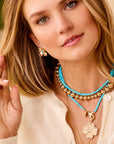 Model wearing gold dogwood studs with turquoise center