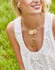 Model wearing layered gold necklaces