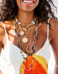 Layered gold and beaded necklaces on model