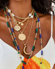 Model wearing various gold and beaded necklaces