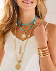 Various gold and turquoise necklaces layered on model