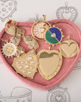 Heart shaped tray filled with assorted love-themed pendants and bracelets, sitting on top of heart sketches.