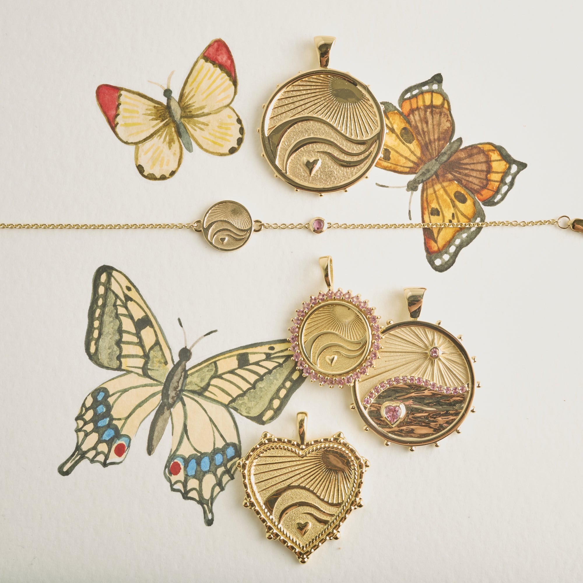 Stylized shot of love, courage, and strength pendants and bracelet on watercolor painting of butterflies