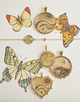 Stylized shot of love, courage, and strength pendants and bracelet on watercolor painting of butterflies