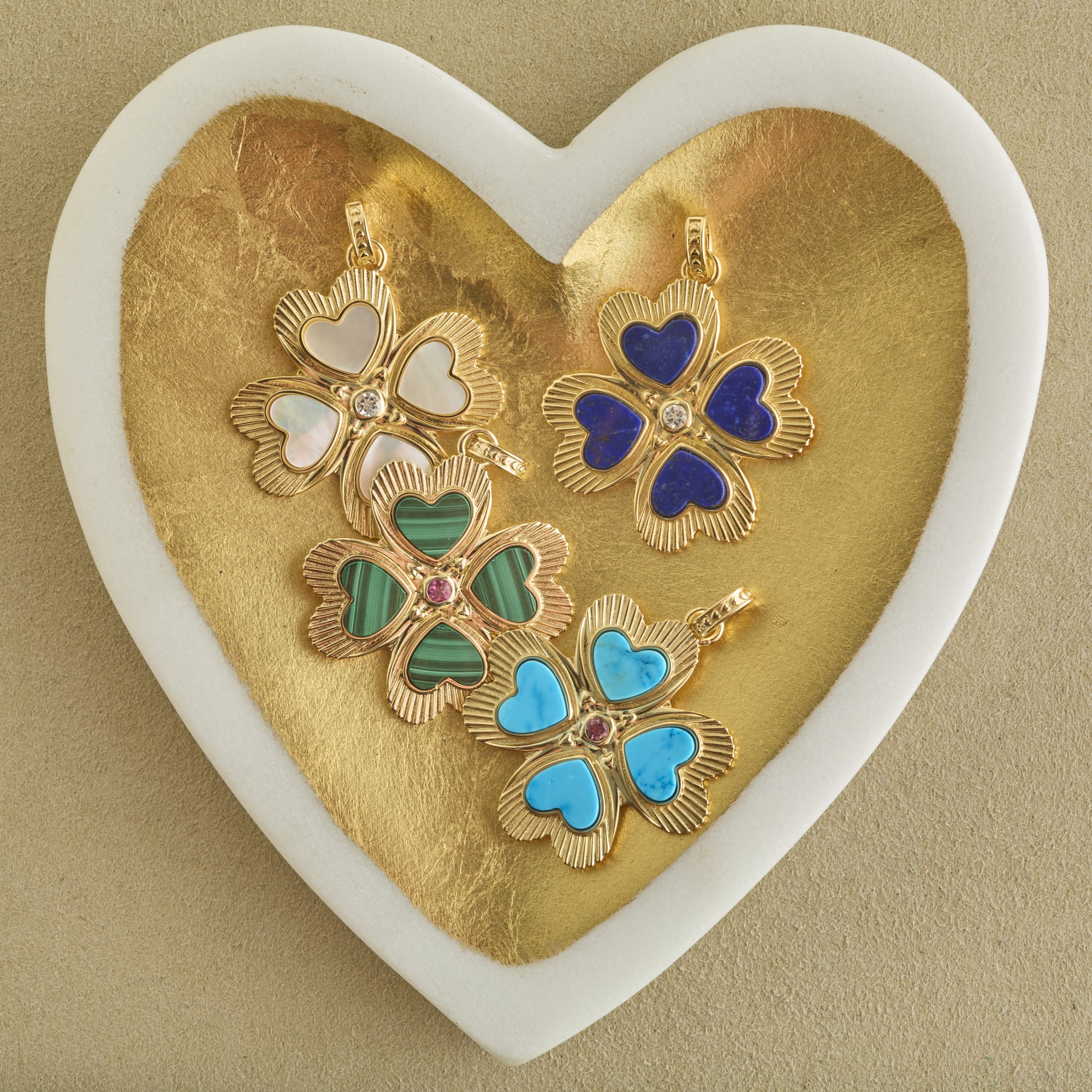 Stylized shot of 4 different clover pendants in gold heart dish
