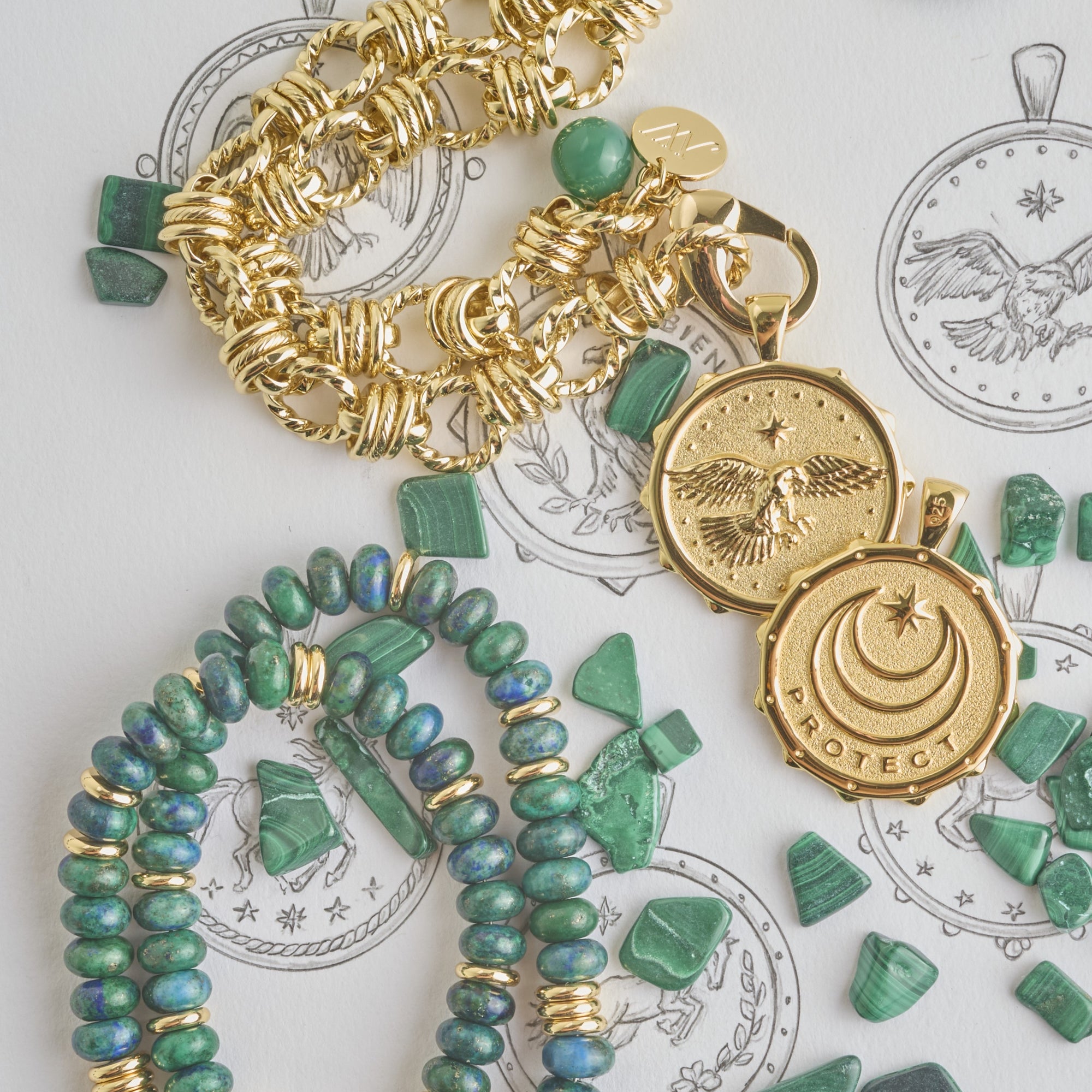 Stylized shot of front and back of eagle coin, gold chain, beaded chain, and malachite pieces on a page of sketches of the coins