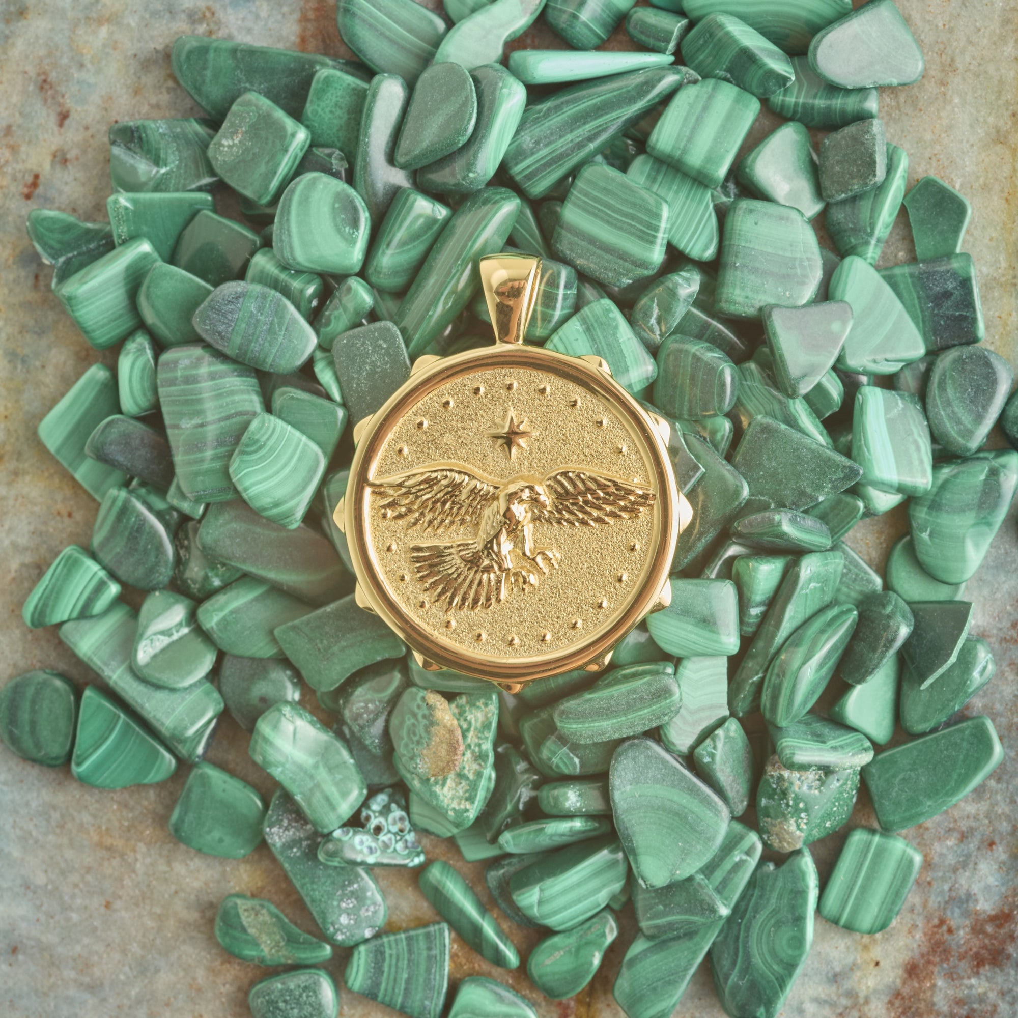 Stylized shot of gold eagle coin pendant on pile of malachite stones