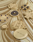 Stylized shot of engravable pendants with sample engravings laid out on gold marbled background
