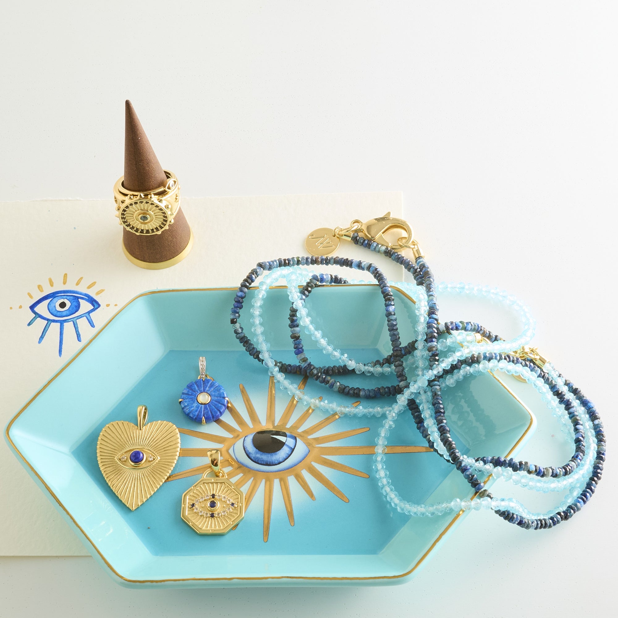 Stylized shot of assorted evil eye pendants, beaded necklaces, and evil eye ring