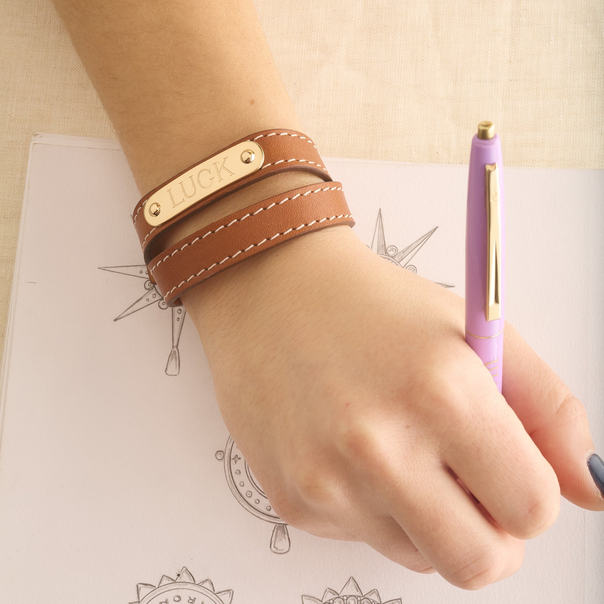 Model wearing brown leather double wrap bracelet with sample engraving of the word LUCK