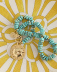 Stylized shot of beaded turquoise necklace with sun coin pendant