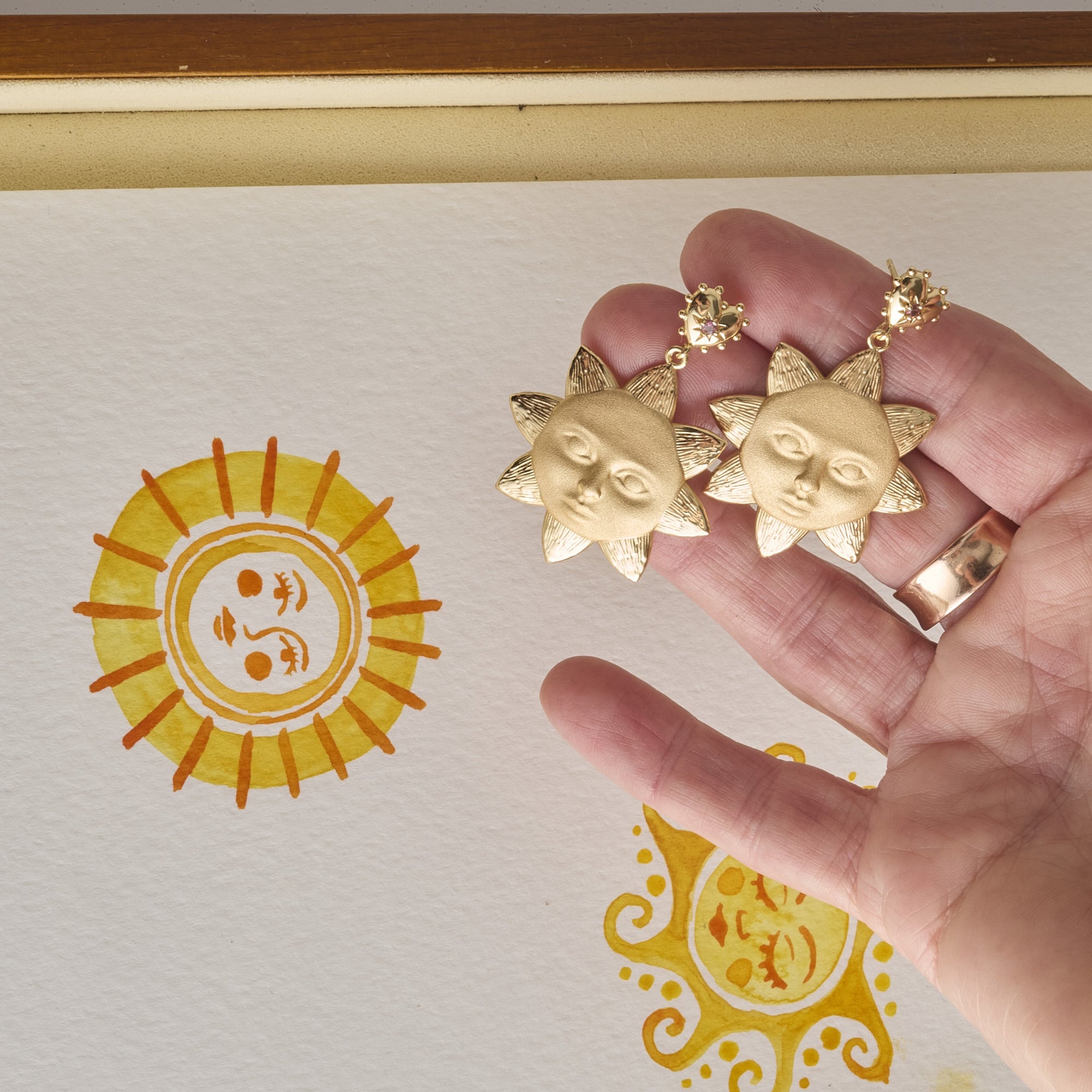 Stylized shot holding sun face drop earrings