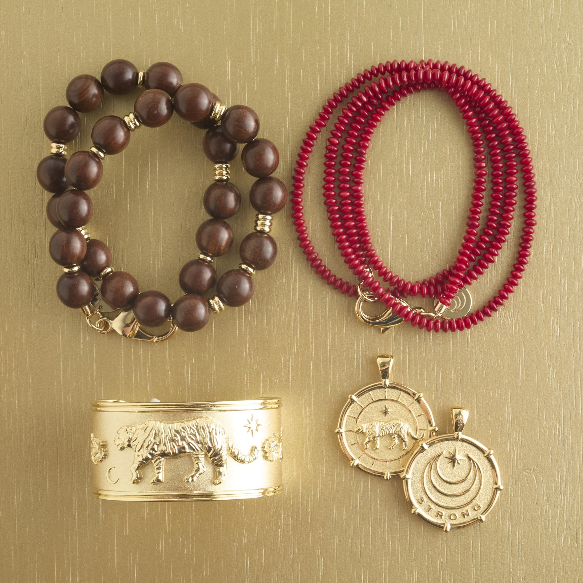 Stylized shot of wood beaded necklace, coral double wrap beaded necklace, tiger cuff, and front &amp; back of tiger coin